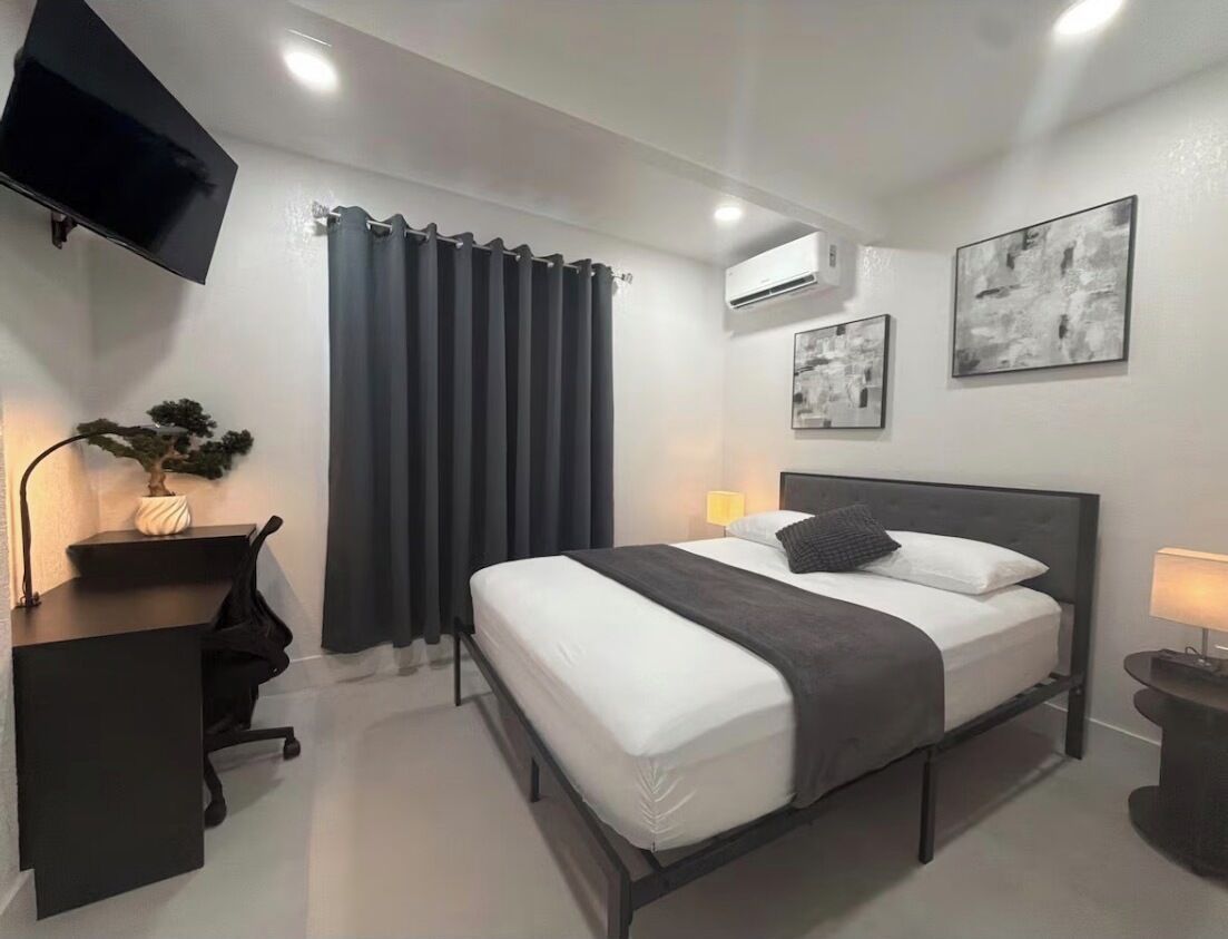 Ein modernes Hotelzimmer mit Bett, Schreibtisch und Fernseher.