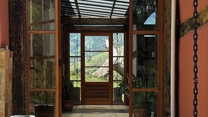 A covered entryway with large glass doors, a wooden door, and a lantern. - Pousada Morada Canto do Sol (São Bento do Sapucaí)