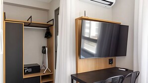 Quarto moderno com escrivaninha, cadeira, televisão de tela plana, armário e abajur.