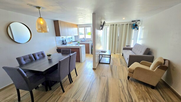 A modern living space with a dining area, kitchen, and seating area.