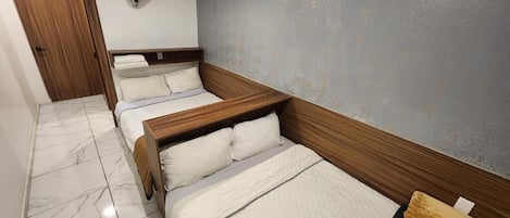 A hotel room with a wooden headboard, a marble floor, and a wall-mounted fan.