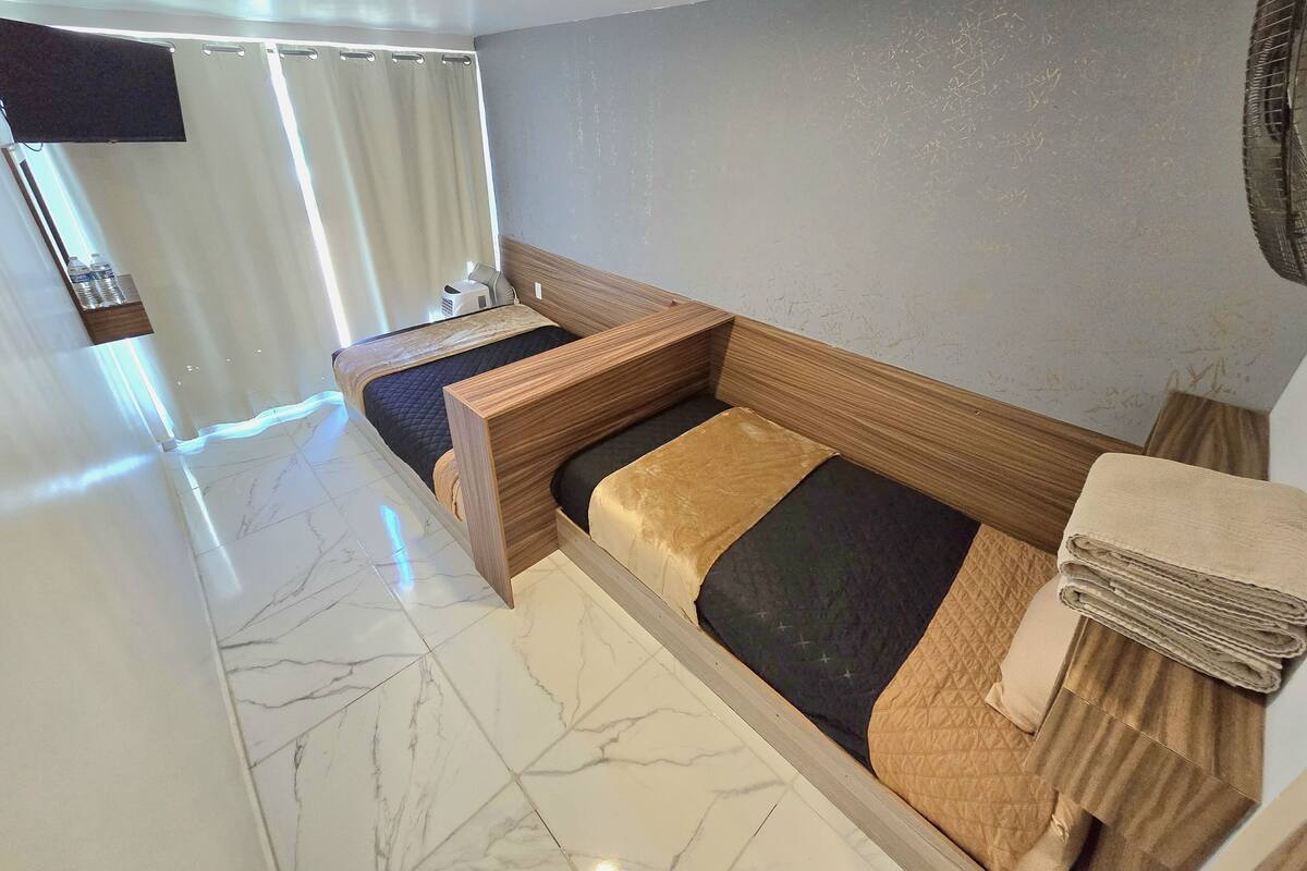 A room with a wooden bed, a small table, a mirror, and a curtain.