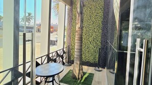 An indoor patio with a glass wall, a palm tree, and a table with chairs.