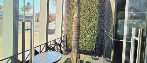 An indoor patio with a glass wall, a palm tree, and a table with chairs.