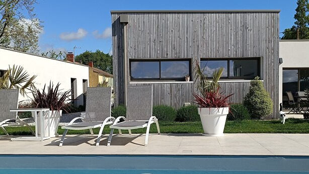A modern building with a pool, outdoor seating, and potted plants. - Bed and breakfast near La Rochelle (Sainte-Soulle)