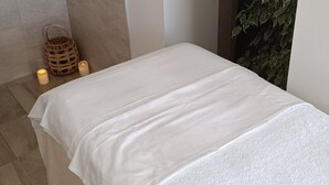 A minimalist room with a bed, a wall-mounted light switch, a small wicker basket, and a potted plant. - Bed and breakfast near La Rochelle (Sainte-Soulle)