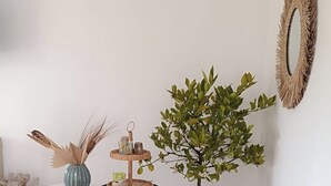 A room with a round table, a blue chair, a potted plant, and a wall-mounted mirror. - Bed and breakfast near La Rochelle (Sainte-Soulle)
