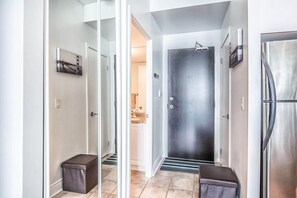 A hallway with a door leading to a bathroom, a trash bin, and a refrigerator. - Amazing Downtown Toronto Condo (Toronto)