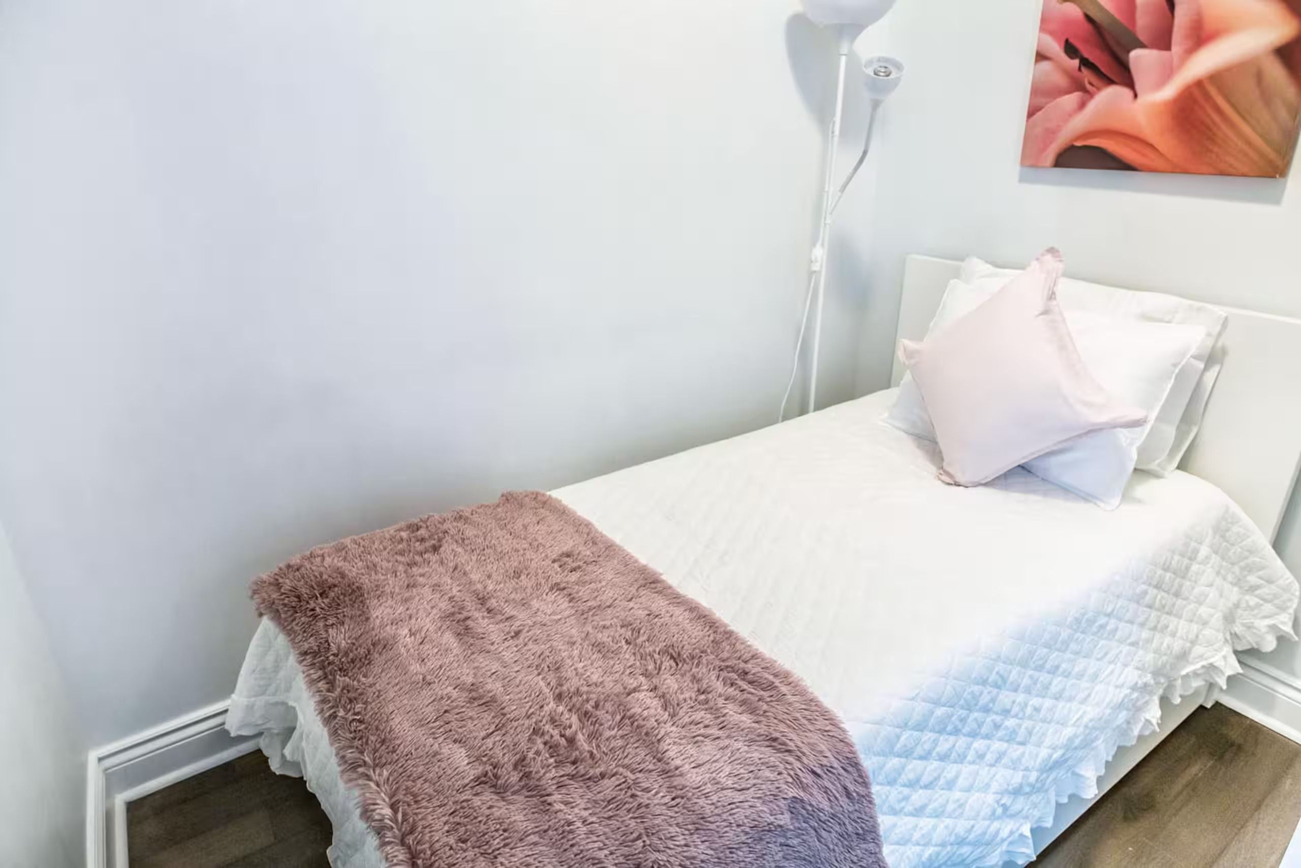 Une chambre à coucher avec un lit, une lampe de chevet et un tableau accroché au mur.