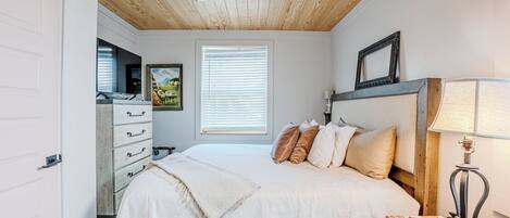 Un dormitorio con cama, ventilador de techo, ventana con persianas, cómoda y lámpara.