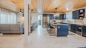 Una cocina moderna con una isla central, armarios oscuros y un suelo con patrón de espiga.
