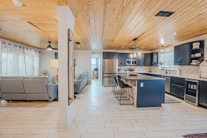 Une cuisine moderne dotée d’un îlot central, de meubles de rangement aux couleurs sombres et d’un plancher au motif en chevrons.
