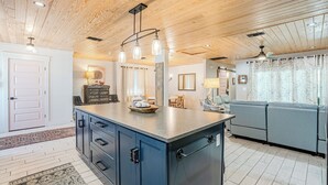 Una cocina moderna con una isla central, techo de madera e iluminación colgante.