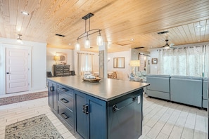 Une cuisine moderne dotée d’un îlot central, d’un plafond en bois et de luminaires suspendus.
