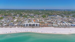 Vista aérea de un pueblo costero con playa, edificios y una estructura prominente en forma de estrella.