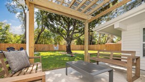 Eine Holzterrasse mit einer Pergola, einer Bank und einem Tisch.