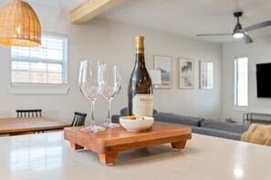 A bottle of Meillon wine on a wooden tray with two glasses and a bowl of fruit. - Sleeps 14 • Outdoor Patio • Firepit • Game Room (Fort Walton Beach)