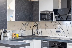 A modern kitchen with a built-in microwave, a coffee machine, and a sink. - Room 'Camera Deluxe' with Wi-Fi and Air Conditioning (Nulvi)