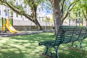 A park with a playground, a green bench, and a tree. - Room 'Camera Deluxe' with Wi-Fi and Air Conditioning (Nulvi)
