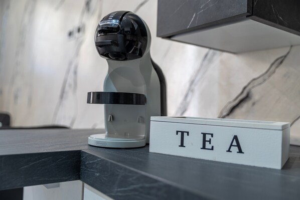 A coffee machine and a 'TEA' sign on a counter.