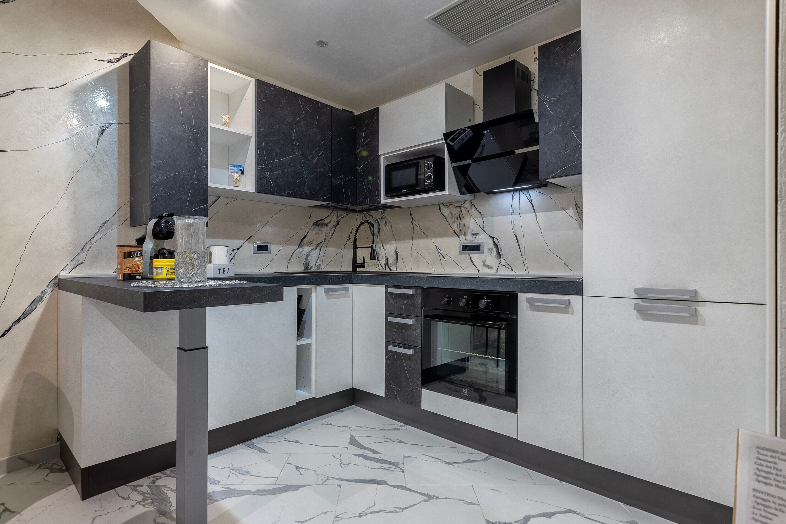 A modern kitchen with a built-in microwave, oven, and a coffee machine on the counter.