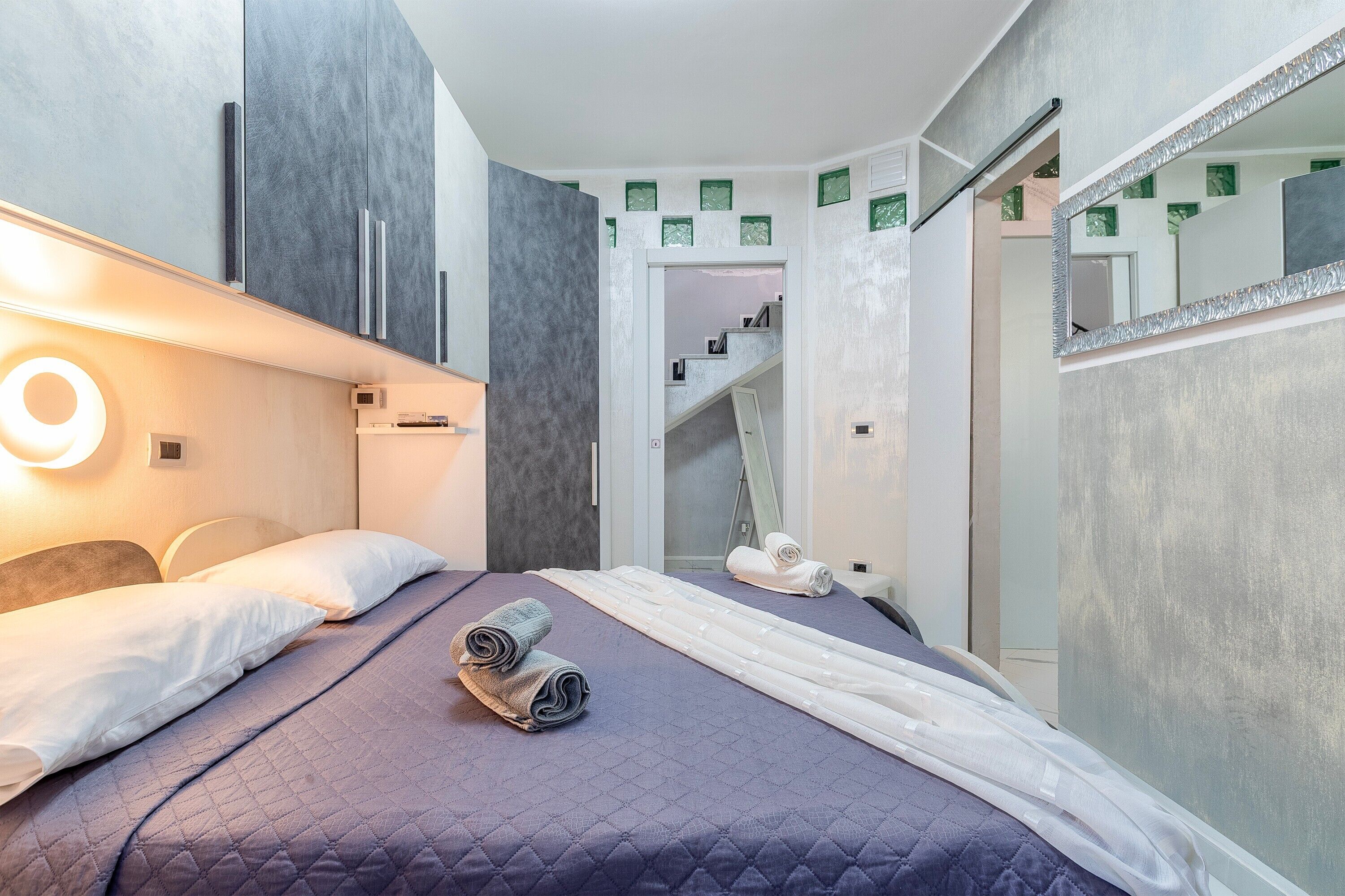 Una camera d'albergo moderna con un letto, un bagno e una scala.
