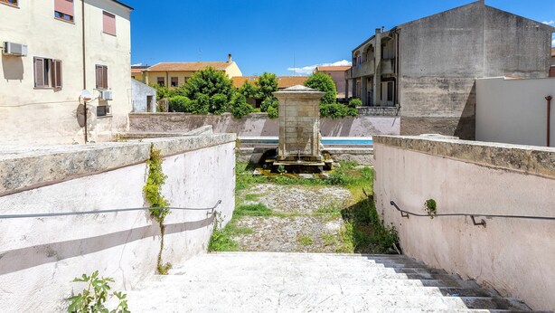 Un carrer estret amb una escala de pedra que condueix a un petit pati interior, envoltat d'edificis amb balcons i aparells d'aire condicionat.