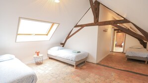 A bedroom with a sloped ceiling, a window, a bed, and a small table. - So Villa La Messagerie (49) - Heated pool - Basketball - 2 hours from Nantes - Sleeps 36. (Noyant)
