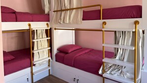 A bunk bed room with a white and gold color scheme, including a headboard, railings, and storage shelves.