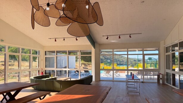 A spacious room with large windows, a wooden table, and a seating area.
