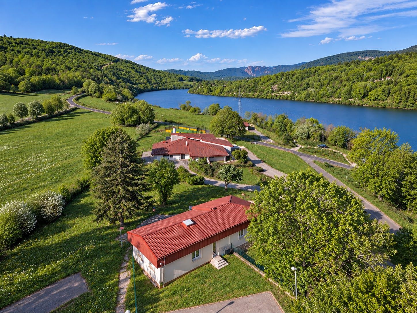 A residential area with a lake, surrounded by greenery and hills.