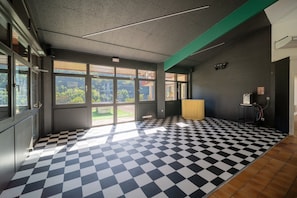 A room with a checkered floor, large windows, and a view of greenery outside.