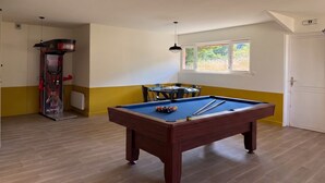 A pool table in a room with a window, a door, and a wall-mounted heater.