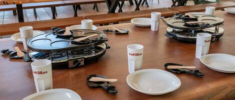 A dining area with multiple tables set for meals, each with plates, cutlery, and branded cups.
