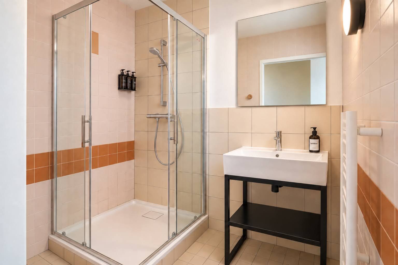 A modern bathroom with a glass-enclosed shower, a white sink, and a mirror above it.