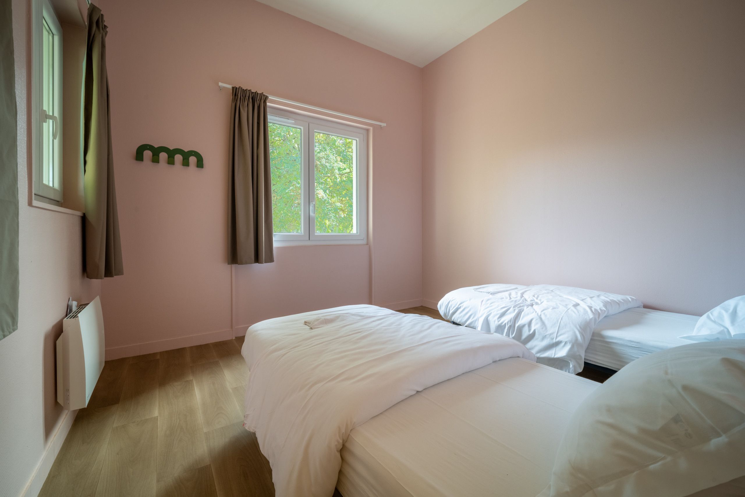 Ein Schlafzimmer mit zwei Betten, einem Fenster mit Vorhängen und einer Heizung.
