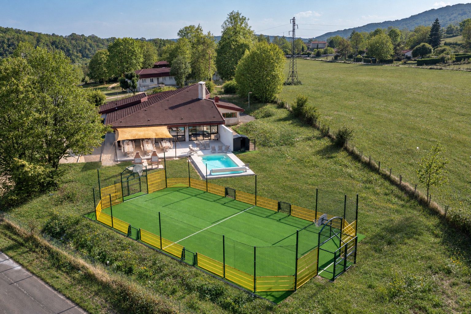 A residential property with a large fenced outdoor area, a swimming pool, and a house with a red roof.