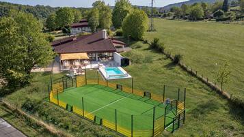 A residential property with a large fenced outdoor area, a swimming pool, and a house with a red roof.