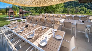 Un espace extérieur aménagé pour les repas, avec des tables et des chaises, une pergola au-dessus et une vue sur le paysage environnant.
