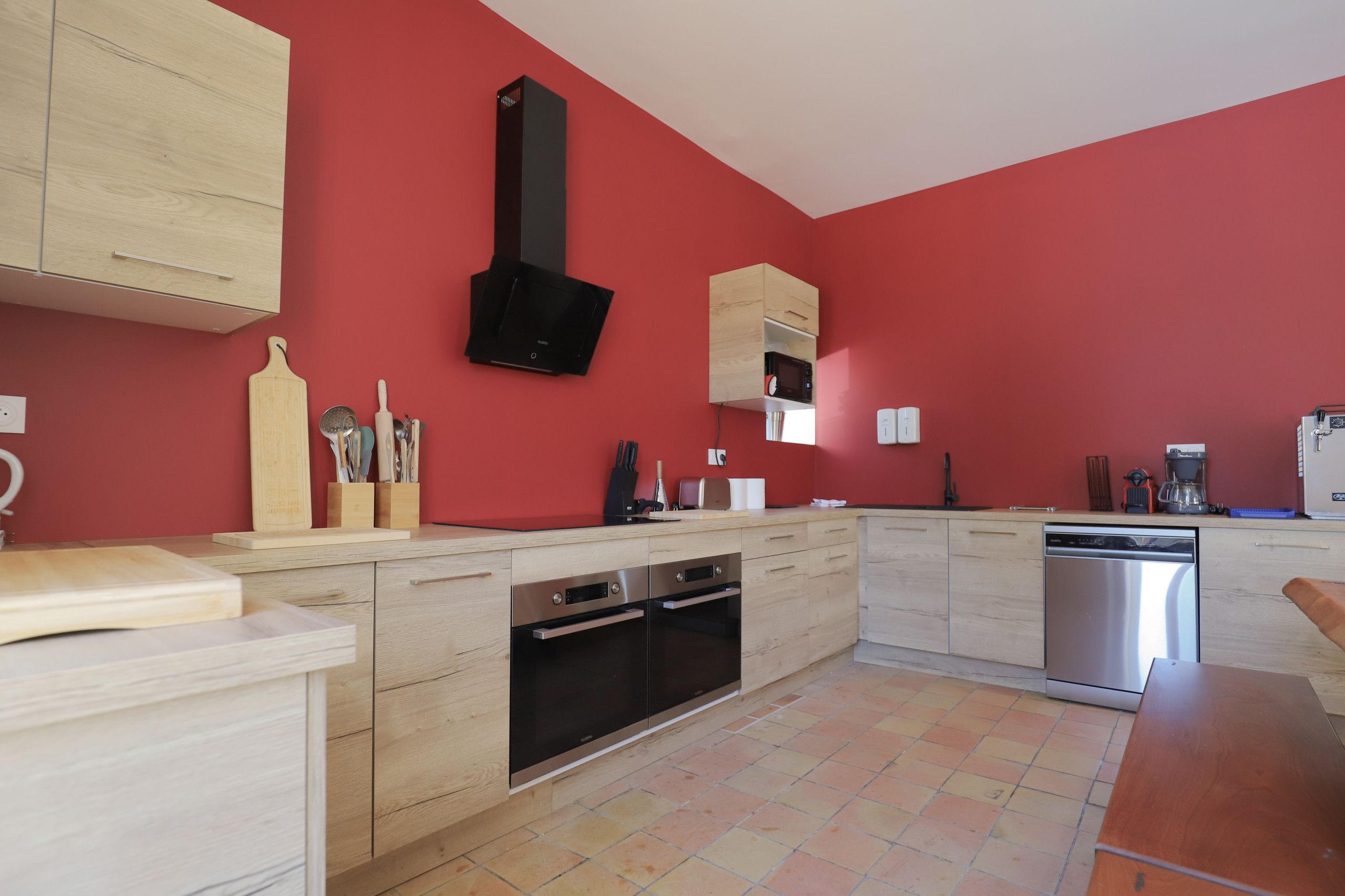 Een moderne keuken met houten kastjes, een zwarte afzuigkap en een ingebouwde magnetron.
