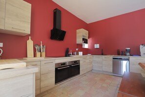 A modern kitchen with wooden cabinets, a black range hood, and a built-in microwave.
