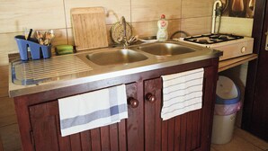 A kitchen with two sinks, a stove, and a trash can.