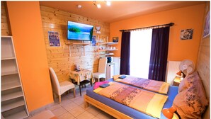 A room with two beds, a TV, a desk, and a chair.