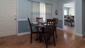 A dining area with a round table, four chairs, and a fire extinguisher on the wall.