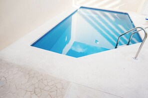 Ein klarer, blauer Pool mit modernem Design, einer Metallleiter und einem gefliesten Boden.