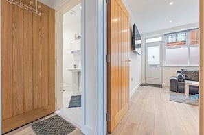 A modern interior with wooden doors, a flat-screen TV, a sofa, and a dining area.