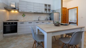 Uma cozinha moderna com forno embutido, fogão a gás e uma área de refeições com mesa e cadeiras.