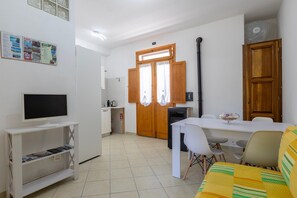 Een moderne keuken met een eethoek, een televisie op een standaard en een bank.