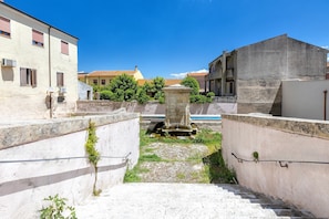 Une ruelle étroite, avec un escalier en pierre menant à une petite cour, entourée d’immeubles dotés de balcons et de climatiseurs.