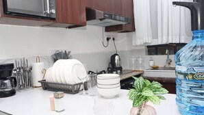 A kitchen with a microwave, kettle, and a large water dispenser. - Makasembo Cozy Serenity (Kisumu)